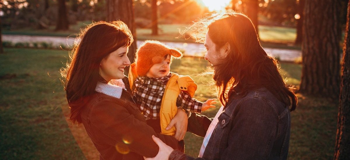 woman in black jacket carrying baby in white and black checkered dress shirt during daytime